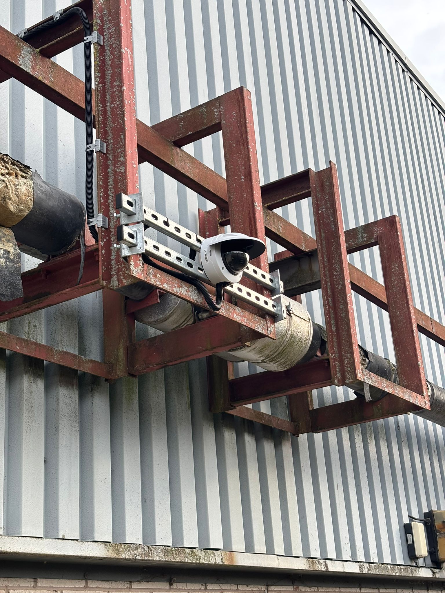 Metallic structure with a camera on a corrugated metal wall