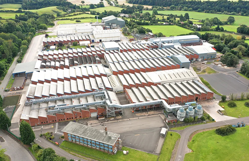 Aerial view of a large industrial complex with multiple buildings surrounded by greenery.