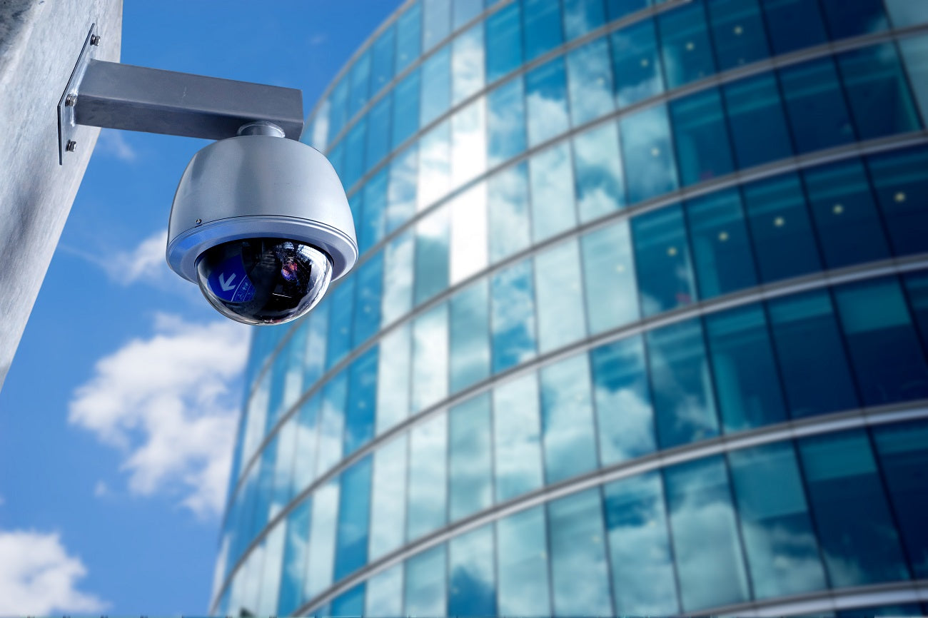 Security camera mounted on a building exterior with a modern glass facade.
