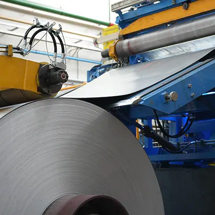 Roll of metal sheet being processed by industrial machinery in a factory setting