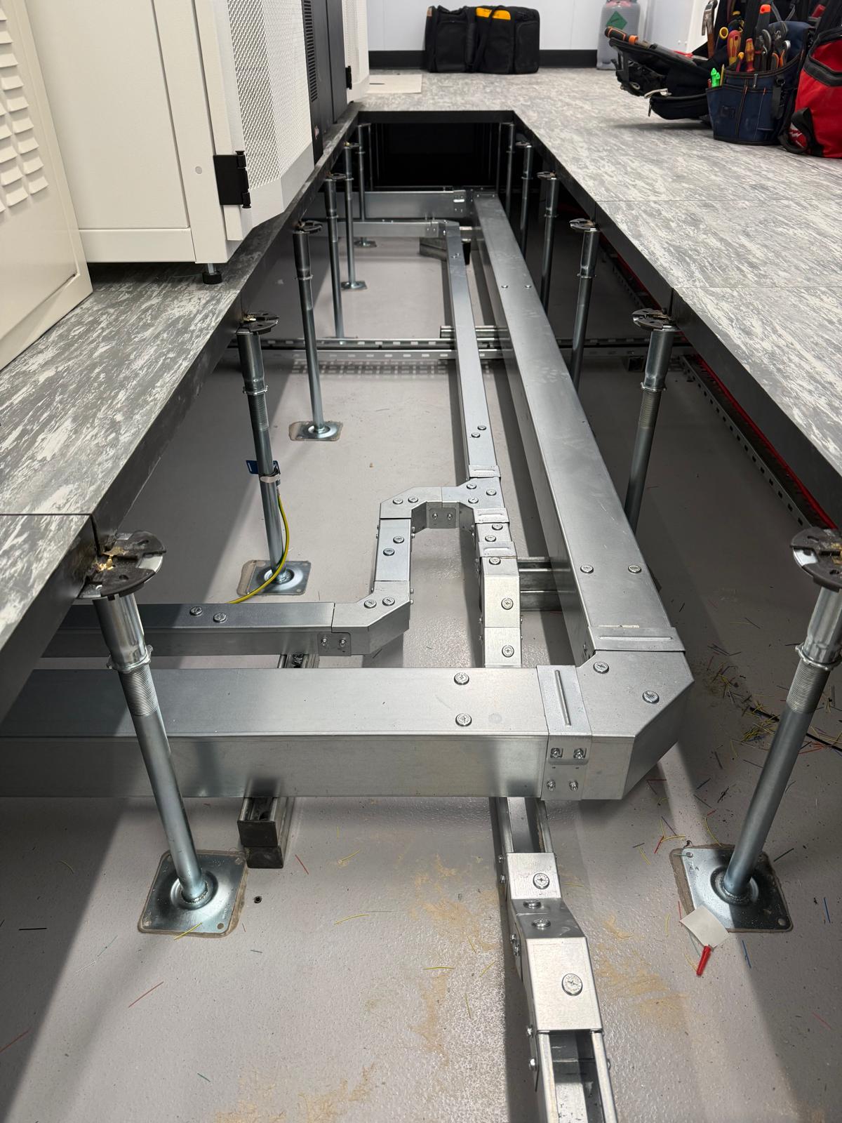 Metal frame structure on a concrete floor with tools and equipment in the background