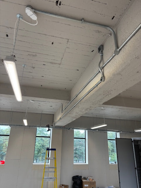 Indoor construction or renovation site with exposed concrete walls and visible pipes.