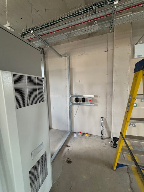 Commercial kitchen exhaust hood with metal frame and filters in a construction setting.